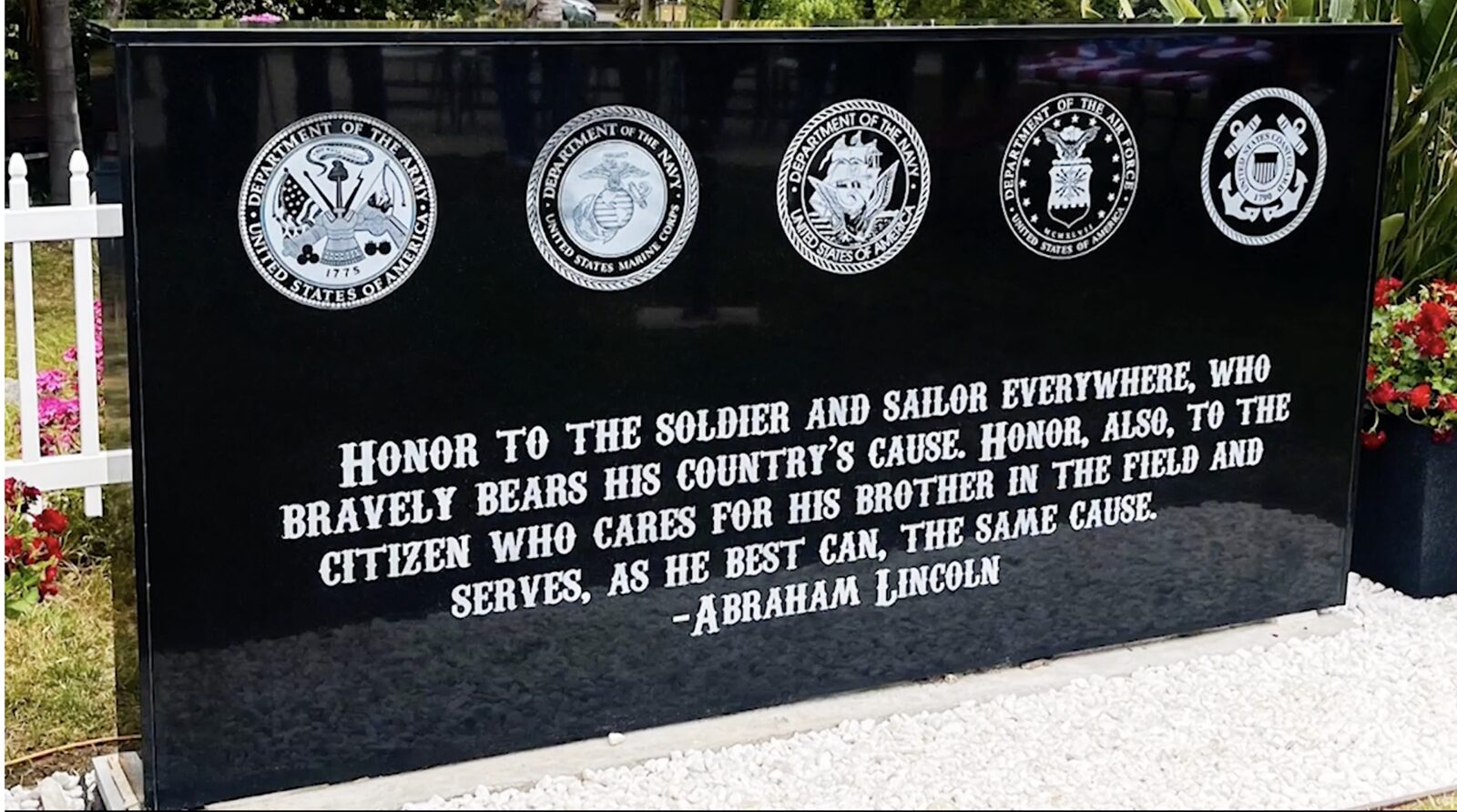 The completed veterans memorial wall: black granite engraved with the five service seals and a Lincoln quotation